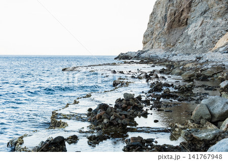 Natural pools with calm blue water along the Red Sea coast in Dahab, Egypt. Rocky shoreline under the Sinai mountains with clear blue water. 141767948
