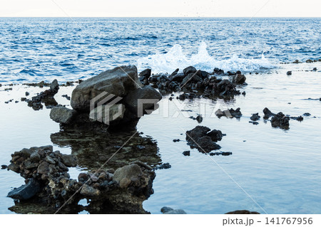 Natural pools with calm blue water along the Red Sea coast in Dahab, Egypt. Rocky shoreline under the Sinai mountains with clear blue water. 141767956