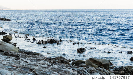 Natural pools with calm blue water along the Red Sea coast in Dahab, Egypt. Rocky shoreline under the Sinai mountains with clear blue water. Natural pools with calm blue water along the Red Sea coast in Dahab, Egypt. Rocky shoreline under the Sinai mountains with clear blue water. 141767957