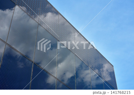 Glass facade reflecting clouds on modern building 141768215