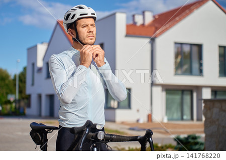 Cyclist fastening bicycle helmet strap before a ride 141768220