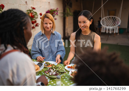 Multi ethnic women friends enjoying outdoor dinner party Multi ethnic women friends enjoying outdoor dinner party 141768299