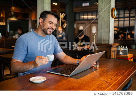 Adult man working on laptop in cafe 141768399