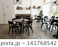 Bright contemporary cafe interior with stylish furniture, large windows, and decorative lighting. Cozy hospitality space prepared for guests in a modern coffee shop 141768542