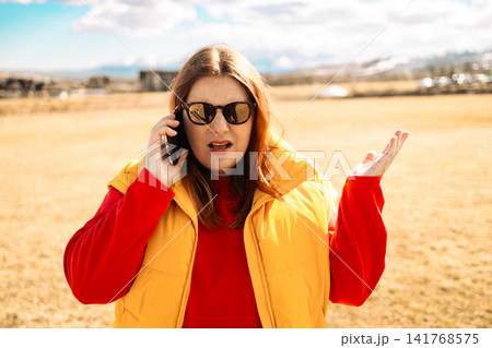 Shocked young woman talking on smartphone outdoors Shocked young woman talking on smartphone outdoors 141768575