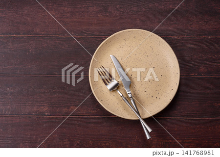 An empty round ceramic plate on a dark, textured brown background. An empty round plate An empty round ceramic plate on a dark, textured brown background. An empty round plate 141768981