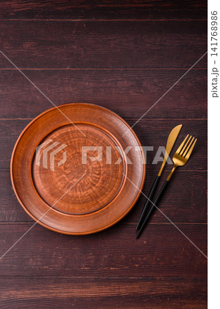 An empty round ceramic plate on a dark, textured brown background. An empty round plate An empty round ceramic plate on a dark, textured brown background. An empty round plate 141768986