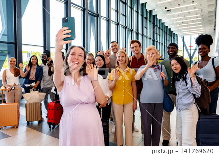 Pregnant woman taking selfie with diverse group of happy travelers in airport Pregnant woman taking selfie with diverse group of happy travelers in airport 141769620