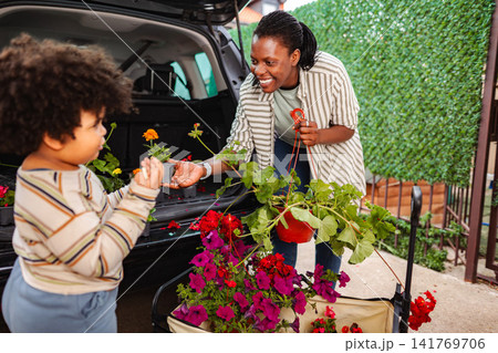 Mother and child unloading flowers from car for gardening 141769706