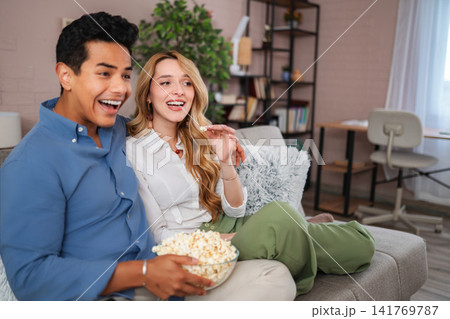 Young couple enjoying movie night with popcorn at home Young couple enjoying movie night with popcorn at home 141769787