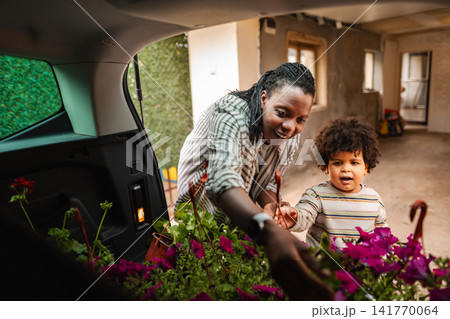 Mother and child unloading flowers from car trunk Mother and child unloading flowers from car trunk 141770064