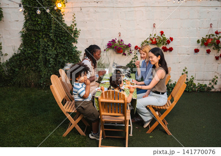 Multi ethnic family friends enjoying backyard summer dinner party Multi ethnic family friends enjoying backyard summer dinner party 141770076