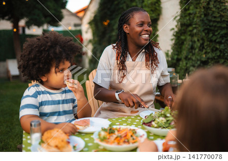 Happy family eating dinner together in their backyard Happy family eating dinner together in their backyard 141770078