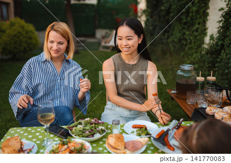 Diverse friends enjoying outdoor barbecue dinner party together Diverse friends enjoying outdoor barbecue dinner party together 141770083