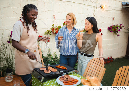 Friends grilling barbecue and drinking wine at backyard party Friends grilling barbecue and drinking wine at backyard party 141770089