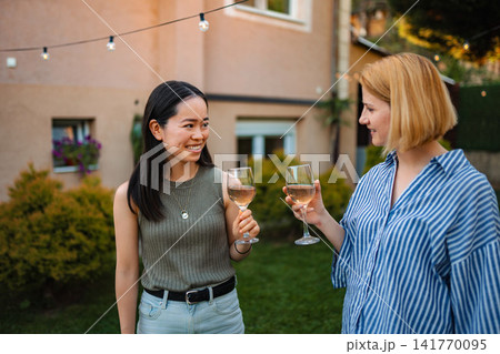 Two happy multi ethnic women toasting rose wine at garden party Two happy multi ethnic women toasting rose wine at garden party 141770095