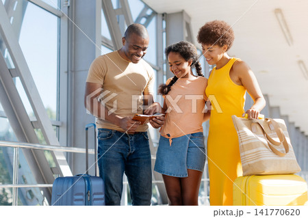 Black family of three checking boarding pass together at airport terminal Black family of three checking boarding pass together at airport terminal 141770620