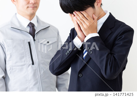 落ち込むリクルートスーツを着た若い男性と作業服のミドル男性 落ち込むリクルートスーツを着た若い男性と作業服のミドル男性 141771425