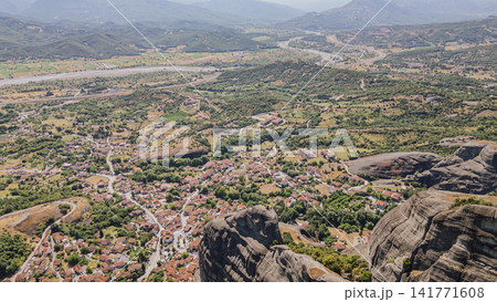High aerial view of Kastraki village with red tile roofs and green Thessaly valley surrounded by Meteora rock pillars in Greece for vacation travel background High aerial view of Kastraki village with red tile roofs and green Thessaly valley surrounded by Meteora rock pillars in Greece for vacation travel background 141771608
