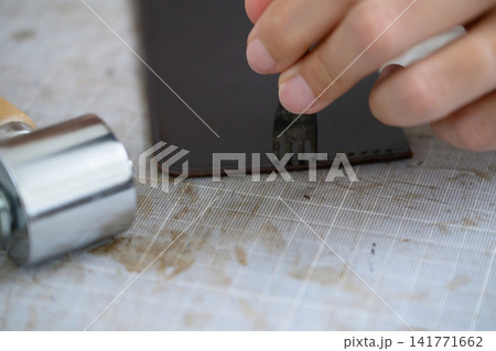 4本菱目打ちで革に縫い穴を開けるレザークラフトの手元 4本菱目打ちで革に縫い穴を開けるレザークラフトの手元 141771662
