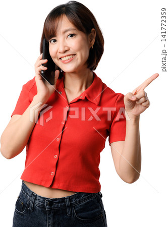 Asian woman holding smartphone red shirt points and smiles while isolated portrait expresses friendly customer support during cheerful Asian woman holding smartphone red shirt points and smiles while isolated portrait expresses friendly customer support during cheerful 141772359