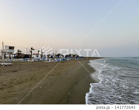 Tourist recreation area, beach umbrellas, beach loungers. Picturesque beach, waves crashing on the sandy shore. Cyprus Island, Mediterranean Sea. 141772645