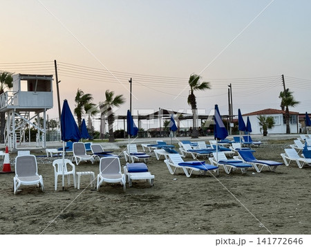 Tourist recreation area, beach umbrellas, beach loungers. Picturesque beach, waves crashing on the sandy shore. Cyprus Island, Mediterranean Sea. Tourist recreation area, beach umbrellas, beach loungers. Picturesque beach, waves crashing on the sandy shore. Cyprus Island, Mediterranean Sea. 141772646