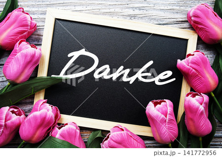 Danke text written on notepad with flower decoration on wooden background Danke text written on notepad with flower decoration on wooden background 141772956