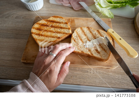 Preparing a grilled ham and cheese sandwich Preparing a grilled ham and cheese sandwich 141773108