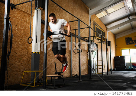 Athletic man doing dips at crossfit gym Athletic man doing dips at crossfit gym 141773462