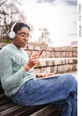 Young black woman online shopping with credit card and tablet outdoors Young black woman online shopping with credit card and tablet outdoors 141773469