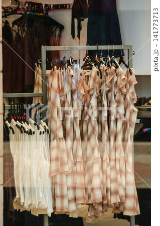 Corby, Northamptonshire, UK - August 2, 2026: Women's dresses and tops displayed in clothing store window Corby, Northamptonshire, UK - August 2, 2026: Women's dresses and tops displayed in clothing store window 141773713