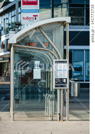 Corby, Northamptonshire, UK - August 2, 2026: Bus stop shelter with passenger information display in Corby town centre, England. Office buildings and business signage are visible in the background. Corby, Northamptonshire, UK - August 2, 2026: Bus stop shelter with passenger information display in Corby town centre, England. Office buildings and business signage are visible in the background. 141773738