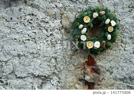 Rustic Christmas Wreath with Dried Citrus and Pine Cones on Stone Wall Rustic Christmas Wreath with Dried Citrus and Pine Cones on Stone Wall 141773806