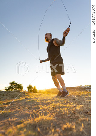 Man skipping rope during sunset in an open field Man skipping rope during sunset in an open field 141773974
