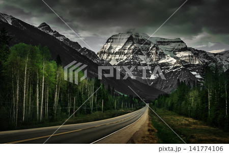 Dramatic Mountain Road Through Forest Under Storm Clouds Dramatic Mountain Road Through Forest Under Storm Clouds 141774106