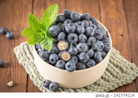 Fresh organic blueberries in a bowl with mint leaf 141774114