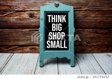 Think Big Shop Small text message with easel on wooden background Think Big Shop Small text message with easel on wooden background 141774252