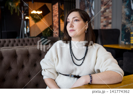 Calm Woman Resting At Table. Serene Female Figure At Cafe Displaying Contemplative Demeanor. Woman In Casual Attire At Cozy Cafe Appears Deep In Reflective Thought With Peaceful Posture Calm Woman Resting At Table. Serene Female Figure At Cafe Displaying Contemplative Demeanor. Woman In Casual Attire At Cozy Cafe Appears Deep In Reflective Thought With Peaceful Posture 141774362