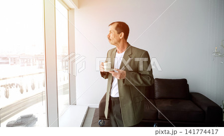 Person Peacefully Enjoys Sunrise With Coffee In Hand. Man Relaxes During Dawn With Warm Beverage In Hand. Individual Finds Tranquility In Morning Sunlight While Sipping Cup Of Coffee Calmly Person Peacefully Enjoys Sunrise With Coffee In Hand. Man Relaxes During Dawn With Warm Beverage In Hand. Individual Finds Tranquility In Morning Sunlight While Sipping Cup Of Coffee Calmly 141774417
