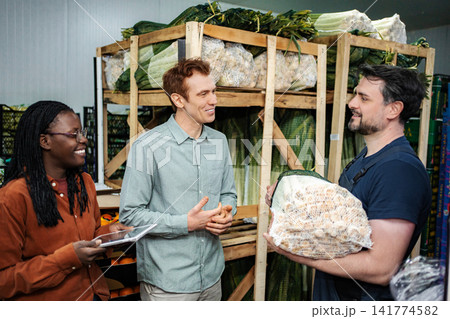 People collaborating in warehouse checking fresh produce inventory People collaborating in warehouse checking fresh produce inventory 141774582
