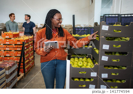 Female worker checking apple inventory in warehouse with tablet Female worker checking apple inventory in warehouse with tablet 141774594