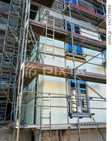 Scaffolding and Exterior Wall Insulation Installation on Modern Residential Building Under Construction 141774868