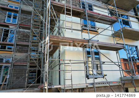 Facade Insulation Installation with Scaffolding at Modern Apartment Building Construction Site Facade Insulation Installation with Scaffolding at Modern Apartment Building Construction Site 141774869