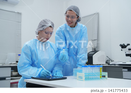 Laboratory Technicians Conducting Experiments with Test Tubes and Digital Device Laboratory Technicians Conducting Experiments with Test Tubes and Digital Device 141775433