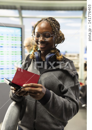 Young woman solo traveler walking through airport terminal with passport, heading toward boarding gate and checking boarding pass. University student flying abroad for vacation, travel culture. Young woman solo traveler walking through airport terminal with passport, heading toward boarding gate and checking boarding pass. University student flying abroad for vacation, travel culture. 141776403