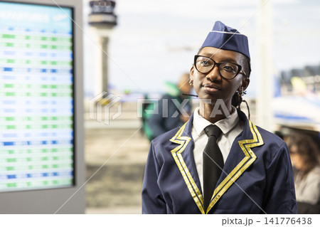 Woman flight attendant, in airline uniform, walking through airport terminal and being ready for takeoff. Aviation personnel highlighting professionalism and air travel quality industry. Woman flight attendant, in airline uniform, walking through airport terminal and being ready for takeoff. Aviation personnel highlighting professionalism and air travel quality industry. 141776438