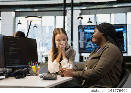 Worried employee sharing concerns with empathetic team leader at desk offering empathetic encouragement. African american woman helping sad coworker, offering comfort in office Worried employee sharing concerns with empathetic team leader at desk offering empathetic encouragement. African american woman helping sad coworker, offering comfort in office 141776462