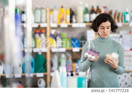 Middle-aged woman choosing scented candles in household store Middle-aged woman choosing scented candles in household store 141777228