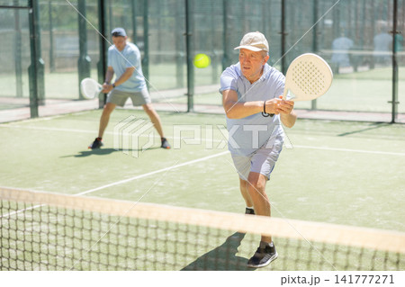 Elderly and adult men playing doubles padel Elderly and adult men playing doubles padel 141777271